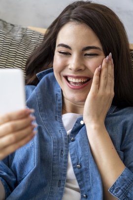 Ex-Freundin schaut lachend auf ihr Smartphone