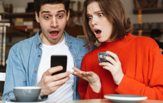 Mann und Frau schauen eifersüchtig aufs Handy