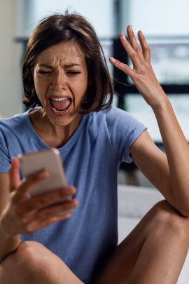 Ex-Partnerin schaut wütend schreiend aufs Smartphone