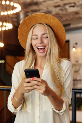 Ex-Freundin im Café schaut lachend aufs Handy
