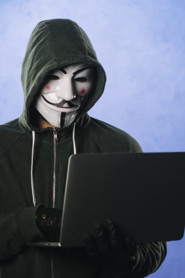 Hacker mit Maske am Laptop