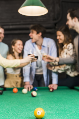 Gruppe von Freunden am Billardtisch stößt mit Drinks an