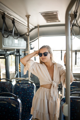 Junge Frau mit Sonnenbrille steht im Bus