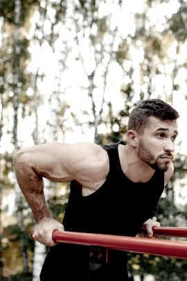 Muskulöser Mann beim Training am Barren im Wald