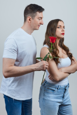 Unsicherer Mann überreicht skeptischer Frau eine Rose