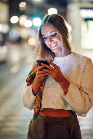Lächelnde Frau liest WhatsApp-Nachricht am Handy