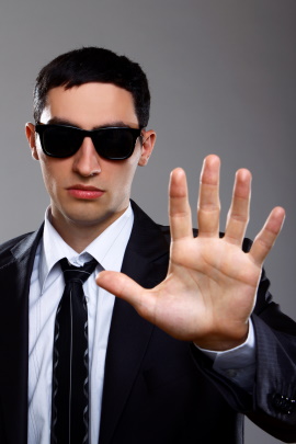 Mann mit Sonnenbrille und Anzug macht Stopp-Geste