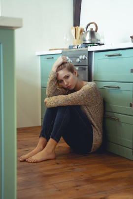 Traurige Frau sitzt allein auf dem Boden in der Küche