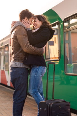 Paar umarmt sich am Gleis des Bahnhofs