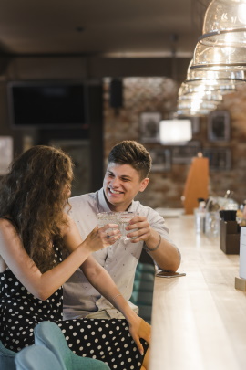 Mann und Frau stoßen mit Drinks an der Bartheke an