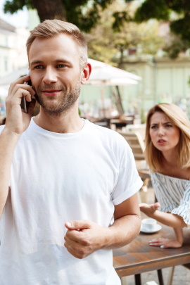 Mann telefoniert mit Handy von verärgerter Frau