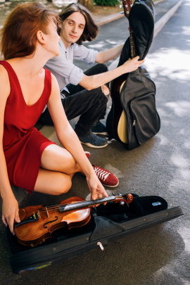 Zwei Straßenmusiker mit Geige und Gitarre schauen sich verliebt an