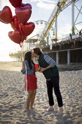 Paar küsst sich am Strand mit Freizeitpark im Hintergrund