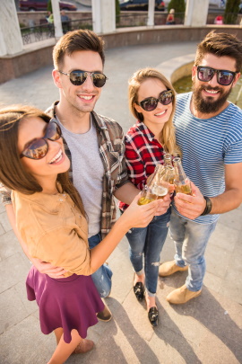 Männer und Frauen stoßen mit Flaschenbier an im Sommer