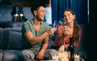 Paar stößt zu Hause bei Kerzenlicht mit Glas Wein an