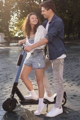 Paar im Frühling steht auf einem E-Scooter in der Stadt