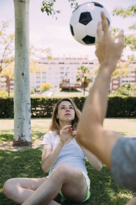 Mann wirft Frau auf der Wiese einen Fußball zu
