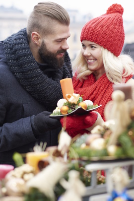Mann schenkt Partnerin eine Kerze auf dem Weihnachtsmarkt
