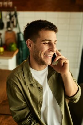 Single-Mann lacht, während er mit jemandem telefoniert