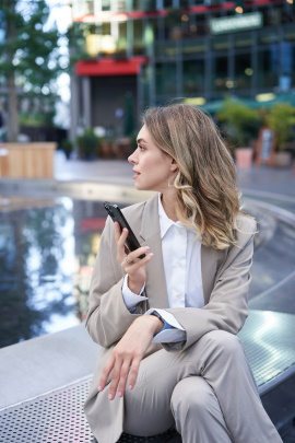 Frau sitzt am Brunnen mit Handy und ghostet Mann