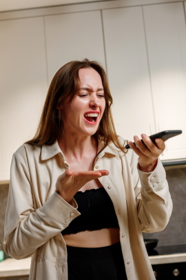 Frau schreit wütend ins Smartphone
