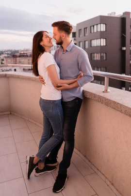 Mann und Frau umarmen sich auf dem Balkon in der Stadt