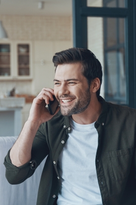 Mann lacht, weil er am Telefon tolle Unterhaltung mit SIngle-Frau führt