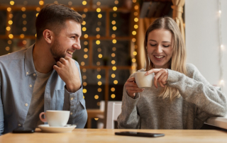 Mann und Frau sitzen lächelnd beim Date im Café