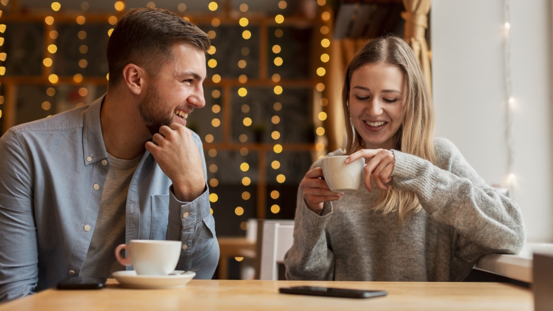 Mann und Frau sitzen lächelnd beim Date im Café
