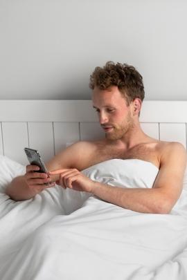 Mann versendet morgendliche SMS während er noch im Bett liegt