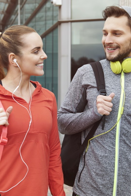 Sportlich gekleidetes Paar in der Stadt lächelt sich an