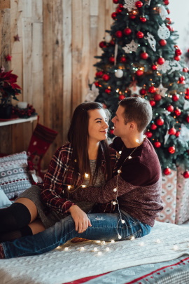 Paar sitzt auf dem Bett mit Weihnachtsbaum im Hintergrund