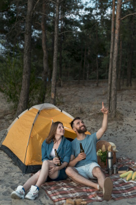 Paar sitzt vorm Zelt am Strand beim Picknick