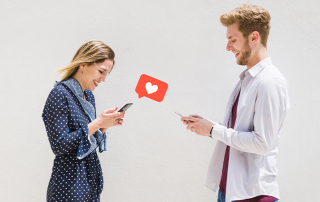 Frau und Mann machen Instagram-Dating und blicken fröhlich aufs Smartphone