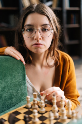 Unfreundliche Frau mit Brille sitzt am Schachbrett