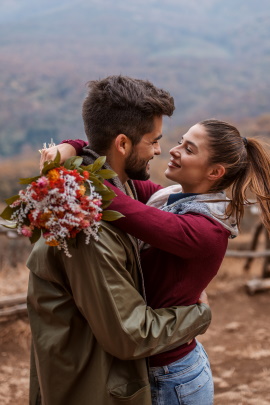 Paar mit Blumenstrauß umarmt sich in der Wildnis