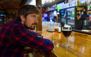 Unglücklicher Mann sitzt alleine an der Bar in einer Kneipe