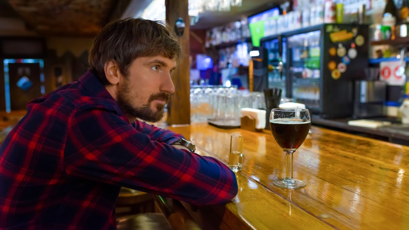 Unglücklicher Mann sitzt alleine an der Bar in einer Kneipe