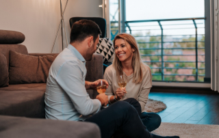 Paar sitzt beim Date zu Hause im Wohnzimmer und trinkt Wein