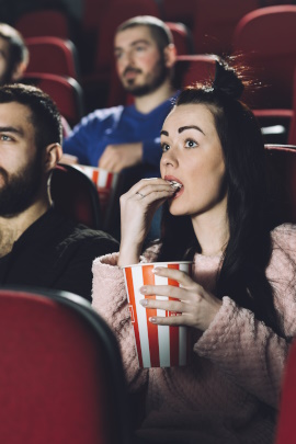 Gestresste Frau sitzt im Kino und schaut auf die Leinwand