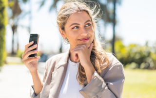 Frech grinsende Frau läuft mit Handy im Park