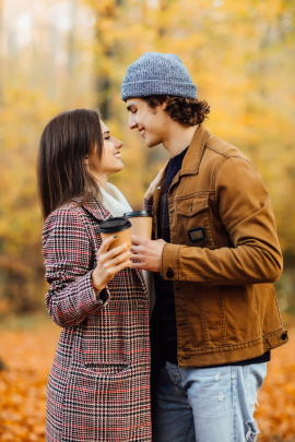 Verliebtes Paar im herbstlichen Park schaut sich lächelnd in die Augen