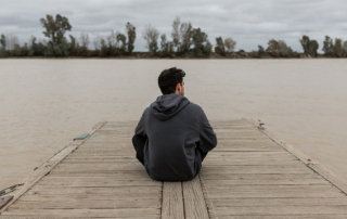 Mann sitzt traurig am Wasser, weil Frau den Kontakt ohne eine Aussprache abgebrochen hat