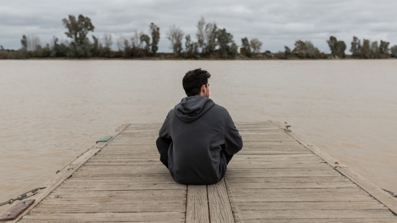 Mann sitzt traurig am Wasser, weil Frau den Kontakt ohne eine Aussprache abgebrochen hat