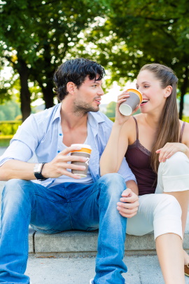 Paar trinkt Kaffee im Park und lacht