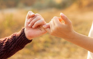 Frau und Mann geben sich mit kleinem Finger ein Versprechen