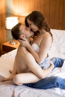 Mann und Frau sitzen küssend auf dem Bett