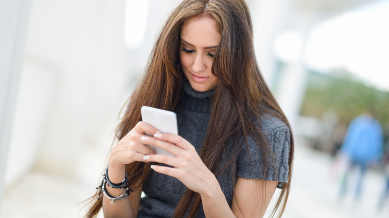 Frau mit Handy wird auf Lovoo angeschrieben