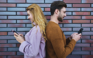 Paar mit Rücken zueinander schaut auf Smartphones