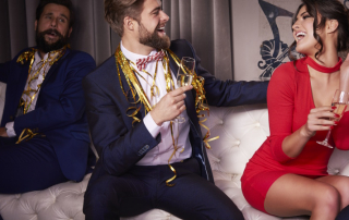 Mann und Frau mit Sektglas sitzen lachend bei einer Party